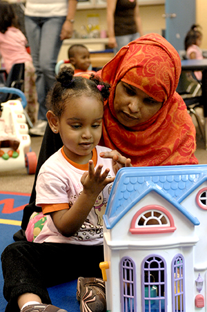 Adult and young child playing on the floor of classroom